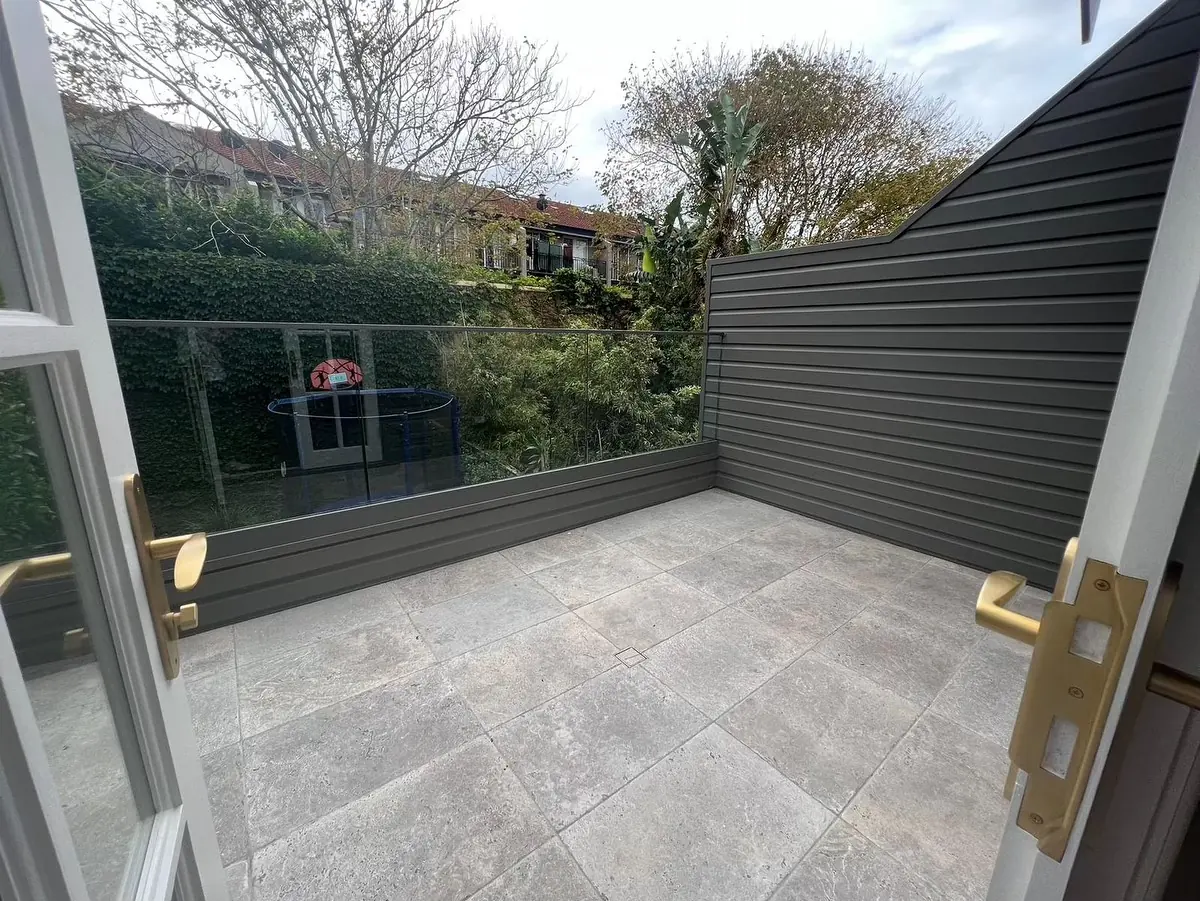 Renovated balcony with pale tiled flooring and dark privacy screen