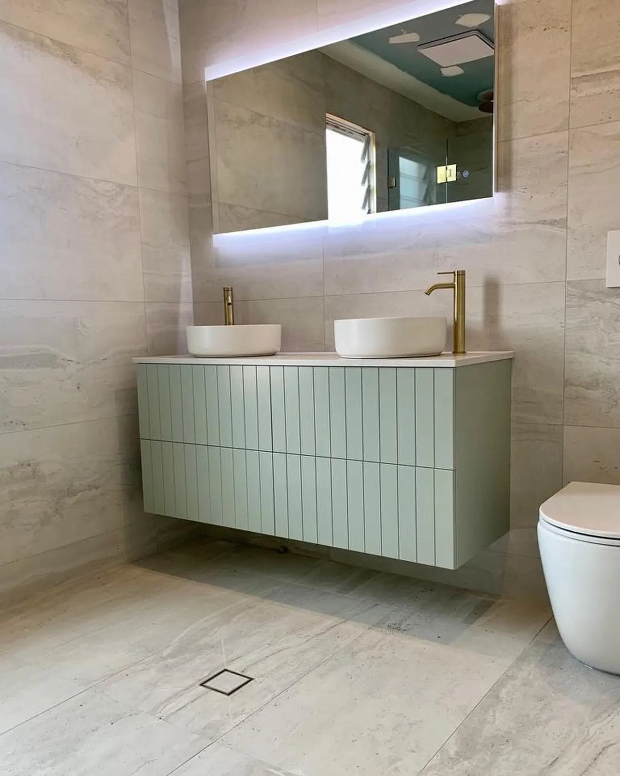Completed bathroom with a curved green vanity
