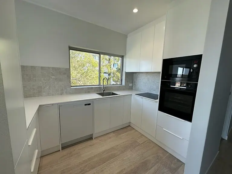 Completed white kitchen renovation with a stone splashback