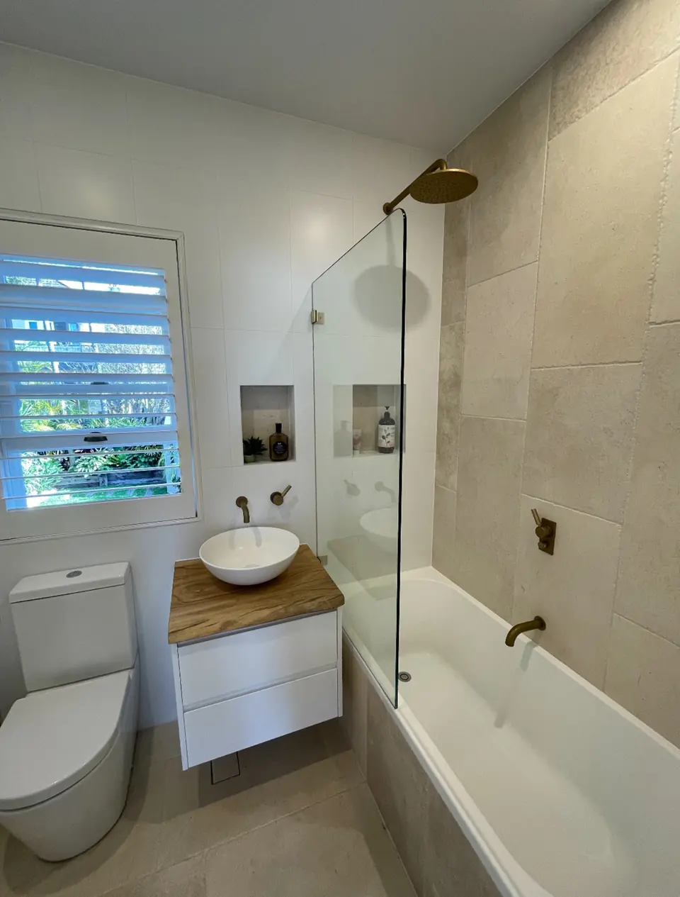 Renovated bathroom with stone look tiles, vessel basin and brass fittings