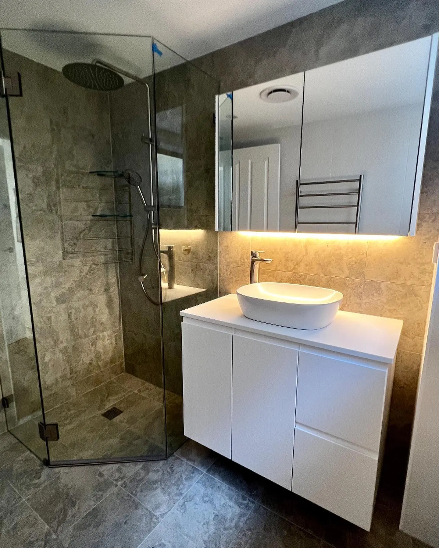Completed stone bathroom with warm mirror lighting