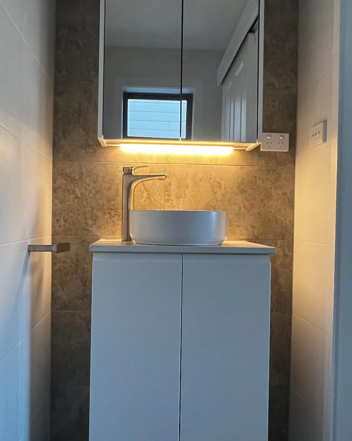 Small bathroom vanity with warm mirror lighting